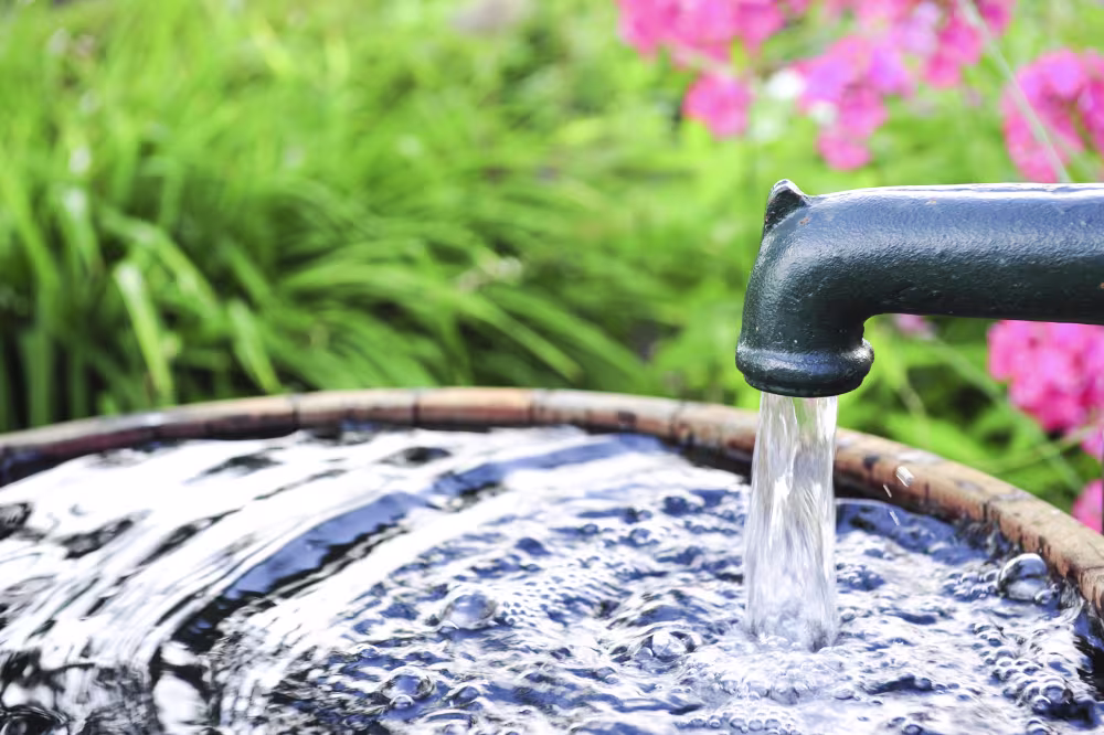 Regenwasser läuft durch ein Rohr in ein Fass