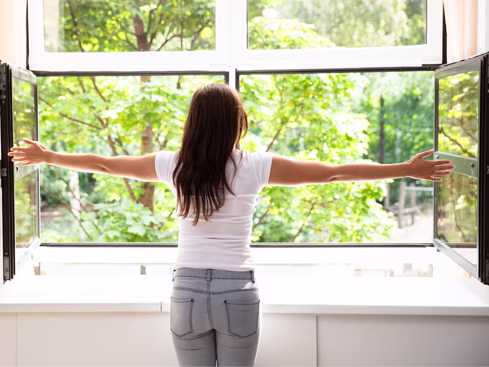 Frau vor geöffnetem Fenster