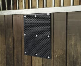 Lifestyle: Schwarze Kratzmatte an Holzwand montiert mit sichtbaren Befestigungsschrauben