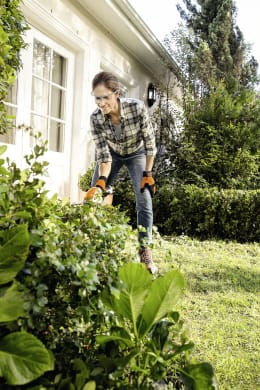 Lifestyle: Frau schneidet mit STIHL Akku-Grasschere HSA 26 Sträucher im Garten