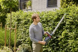 Lifestyle: Mann schneidet Hecke mit GARDENA Akku-Heckenschere ComfortCut im Garten