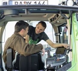 Lifestyle: Techniker erklärt Landwirt die Bedienung eines ISOBUS-Terminals in der Traktorkabine