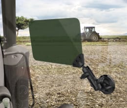 Lifestyle: Sonnenblende mit Saugnapfhalterung an Fahrzeugscheibe montiert, Blick auf Feld mit Traktor