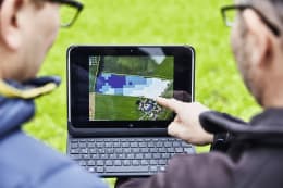 Detailbild: Zwei Personen betrachten digitale Feldkarte mit Ertragsdaten auf Tablet im Freien