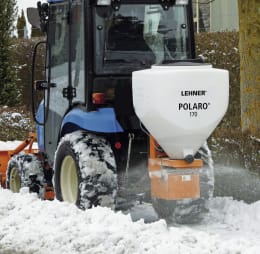 Produktbild: LEHNER® Winterdienststreuer Polaro® E mit weißem Behälter, montiert an Traktor im Wintereinsatz