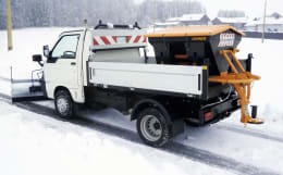 Produktbild: LEHNER® Winterdienststreuer Polaro® in Schwarz-Orange auf Fahrzeug montiert im Wintereinsatz