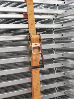 Lifestyle: Orangefarbener Zurrgurt mit Ratsche sichert Metallgestell bei Transport