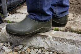 Lifestyle: Person trägt olivgrüne nora Gartenschuhe Comfy bei der Gartenarbeit auf Steinplatten