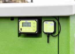Lifestyle: SmartCoop Steuerung mit Display und WLAN-Modul montiert an grüner Stallwand