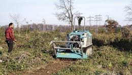 Lifestyle: Pfanzelt Forstraupe Moritz bei der Geländearbeit mit Mulchgerät, Bediener daneben stehend