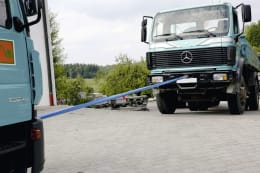 Lifestyle: Blaue Abschleppschlinge verbindet zwei LKW bei einer Abschleppdemonstration im Freien