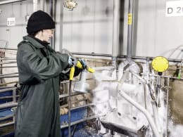 Lifestyle: Person reinigt Metalloberflächen mit Kärcher Hochdruckreiniger und Aktivreiniger in Industrieumgebung