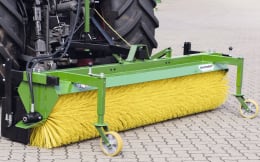 Produktbild: Düvelsdorf Kehrmaschine Stratos in Grün mit gelben Bürsten, montiert an Hoflader