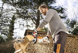 Lifestyle: Mann sägt Brennholz mit STIHL Akku-Kettensäge MSA 70 C-B im Garten