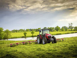 Lifestyle: Massey Ferguson Traktor mit Heuwender bei der Arbeit auf grüner Wiese