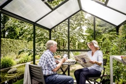 Lifestyle: Paar entspannt im Gewächshaus mit Kaffee und Zeitung im Garten
