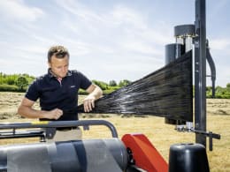 Lifestyle: Landwirt prüft Wickelfolie am Ballenwickelgerät auf dem Feld