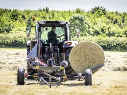 Lifestyle: Massey Ferguson Ballenwickelgerät im Einsatz auf dem Feld mit Rundballen