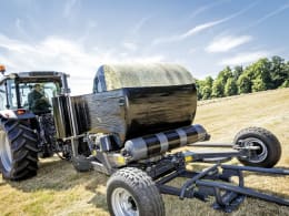 Produktbild: Massey Ferguson Ballenwickelgerät im Einsatz beim Wickeln eines Rundballens mit schwarzer Folie