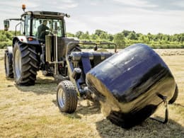 Produktbild: Massey Ferguson Ballenwickelgerät im Einsatz mit eingewickeltem Rundballen auf dem Feld