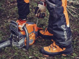 Lifestyle: Person mit Husqvarna® Benzin-Kettensäge bei der Waldarbeit mit Schutzkleidung und Handschuhen