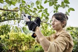 Lifestyle: Frau schneidet mit STIHL Akku-Astschere ASA 20 Äste im Garten mit Schutzbrille