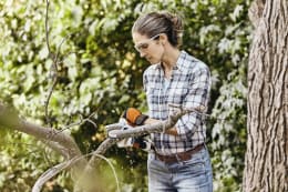 Lifestyle: Frau sägt mit STIHL Akku-Astsäge GTA 26 einen Ast im Garten