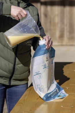 Lifestyle: Person füllt Kolostrum aus transparentem Beutel in TRUSTI® Ersatzbeutel um