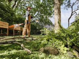 Lifestyle: Person mit Schutzhelm schneidet Baumäste im Garten mit STIHL Akku-Hochentaster HTA 30
