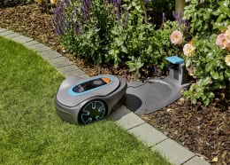 Lifestyle: GARDENA Mähroboter SILENO minimo mit Ladestation im Garten neben Blumenbeet