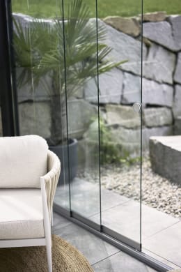 Lifestyle: Glasschiebewand an Pergola mit Lounge-Sessel im Garten