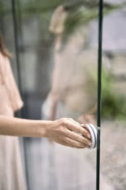 Lifestyle: Hand öffnet Glasschiebewand einer Pergola im Garten