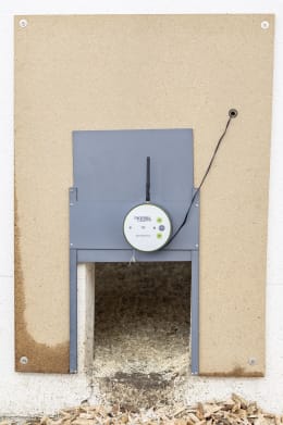 Produktbild: KERBL Hühnerklappe Duo Smart Plus mit WLAN-Steuereinheit und Führungsschienen, montiert an Holzwand