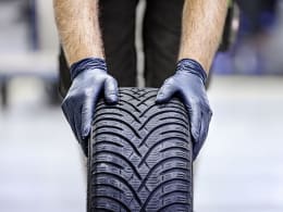 Lifestyle: Hände mit schwarzen Nitril-Einmalhandschuhen greifen einen Autoreifen