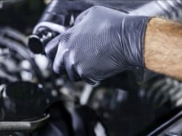 Produktbild: Schwarze Nitril-Einmalhandschuhe mit strukturierter Grip-Oberfläche bei Werkstattarbeit