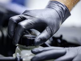 Produktbild: Schwarzer Nitril-Einmalhandschuh mit strukturierter Grip-Oberfläche an Hand bei Arbeitseinsatz