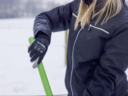 Lifestyle: Person mit Aluschaufel mit Holzstiel beim Schneeschaufeln