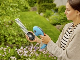 Produktbild: GARDENA Akku-Grasschere PowerCut 20 in türkis mit Strauchscherenmesser im Einsatz