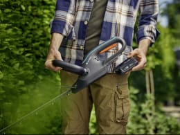 Lifestyle: Mann hält GARDENA Akku-Heckenschere EasyCut 55 im Garten