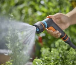 Lifestyle: Hand hält GARDENA Multifunktionsbrause Classic Compact beim Bewässern von Pflanzen im Garten