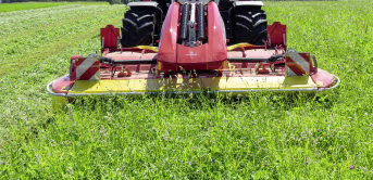 Lifestyle: Pöttinger Scheibenmähwerk im Einsatz auf einer grünen Wiese, Frontansicht mit Traktor