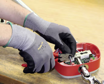 Lifestyle: Hände mit Arbeitshandschuhen bei Feinmontage an Elektronikgerät