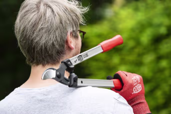 Lifestyle: Person schneidet Ast mit FELCO Zweihand-Astschere im Garten