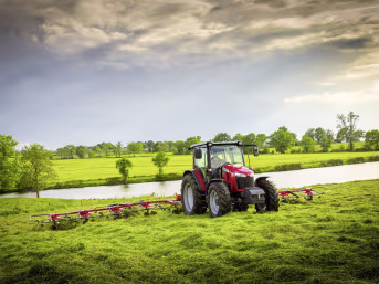 Lifestyle: Massey Ferguson Traktor mit Heuwender bei der Arbeit auf grüner Wiese