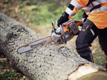 Produktbild: Husqvarna Akku-Kettensäge 550i XP in orange-schwarz beim Sägen eines Baumstamms