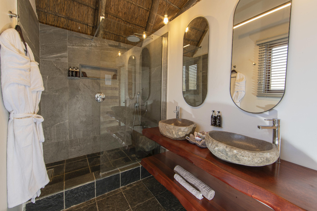 En-suite walk-in shower and double stone basins at Muchenje Safari Lodge