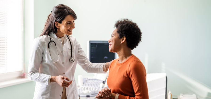 A doctor confirms good news to a patient while gently touching her back