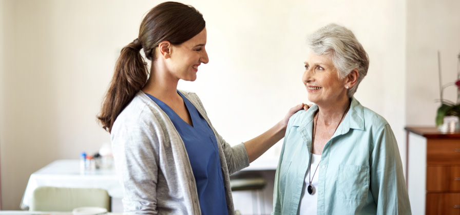 A tech and resident smile at each other in the dining room of an assisted living facility