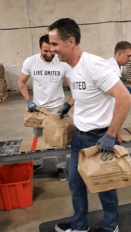 BeachFleischman, Pinnacle Plan Design, and MOD Ventures staff work an assembly line in the Community Food Bank warehouse