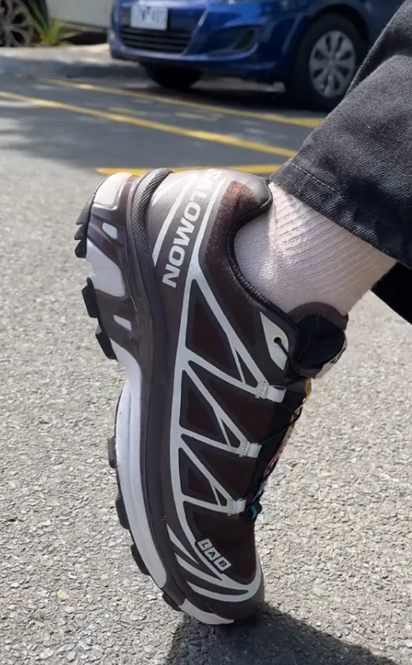 Woman wearing brown and grey Salomon XT-6 sneakers, back view
